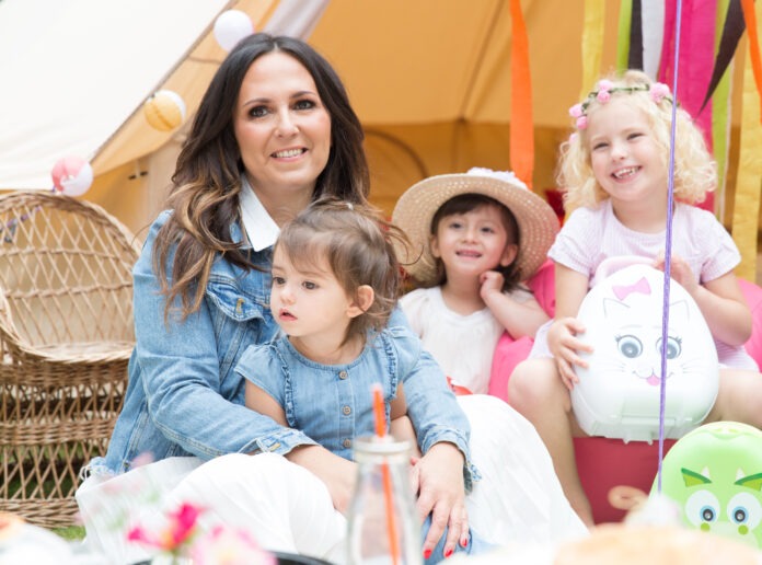Potty Training teacher Amanda Jenner sits on a floor, with three small children around her.