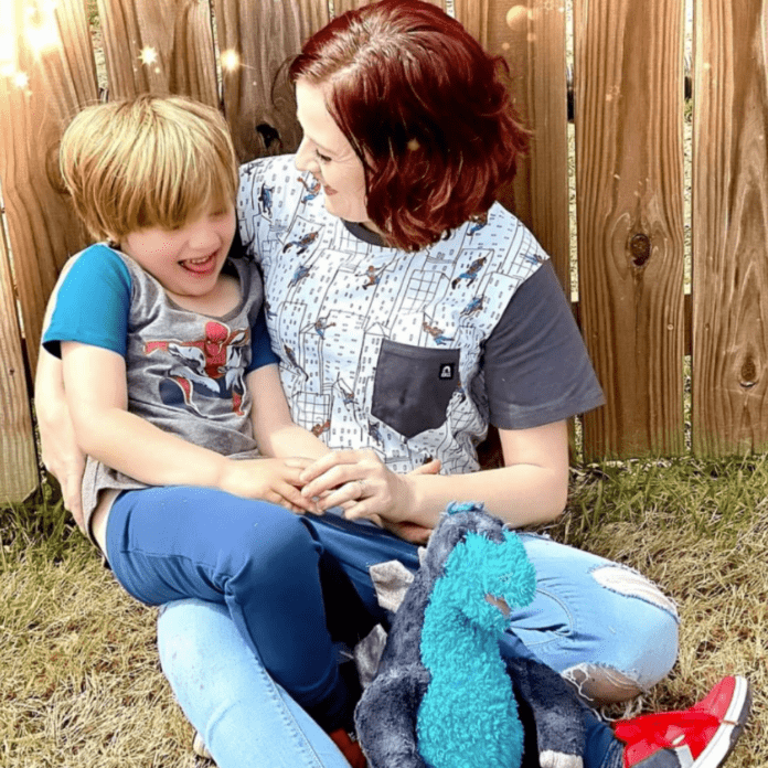 A photo of Alicia and her son. They are both wearing short-sleeved shirts and Alicia is smiling at her son