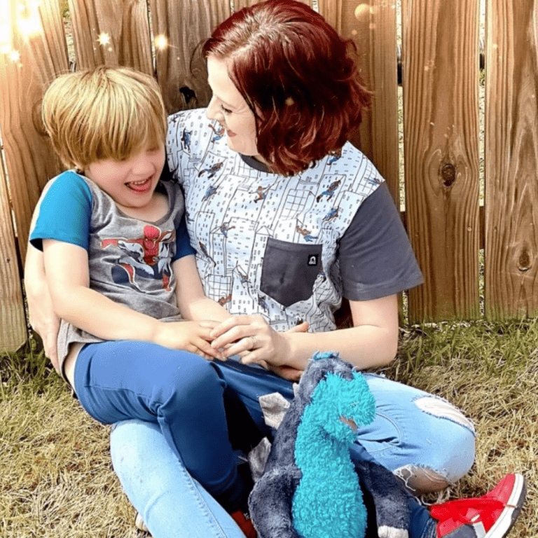 A photo of Alicia and her son. They are both wearing short-sleeved shirts and Alicia is smiling at her son